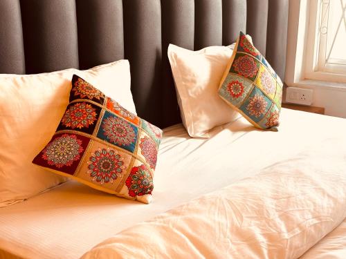 dwie poduszki siedzące na łóżku w obiekcie Sailani Lostels w mieście Rishikesh