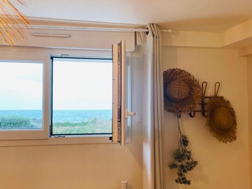 a bathroom with a window with a view of the ocean at Beach House 50 in Omonville-la-Rogue