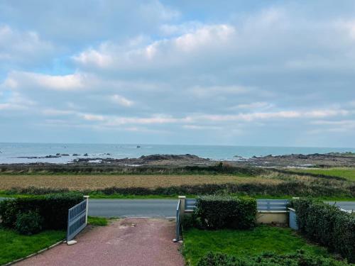 a bench on a road with the ocean in the background at Beach House 50 in Omonville-la-Rogue