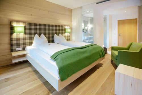 a bedroom with a large bed and a green chair at Hotel Gasthof zur Post in Sankt Gilgen