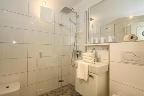 a white bathroom with a toilet and a sink at Wattkoje-Ein-Appartement-der-besonderen-Art-erwartet-Sie-am-Rande-der-Braderuper-Heide in Braderup