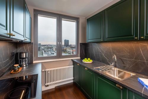 a kitchen with green cabinets and a large window at The Tale Luxury Suites in Berlin