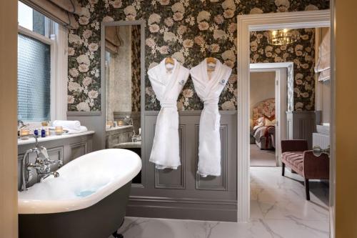 uma casa de banho com banheira e 2 vestidos brancos em exposição em Killashee Hotel em Naas