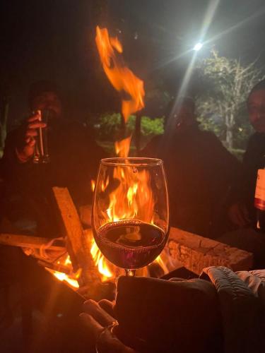 a glass of wine sitting next to a fire at Alinda House Naukuchiatal by THE GHAUR in Bhīm Tāl