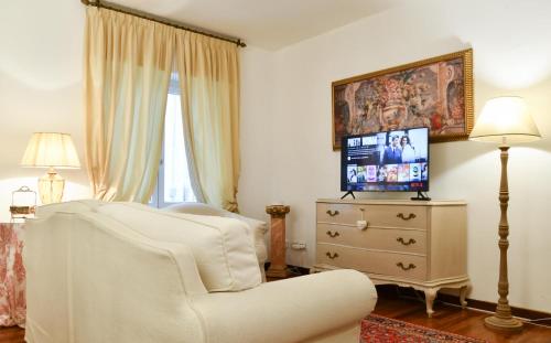 un salon avec une chaise blanche et une télévision dans l'établissement Emily Luxury Apartment, à Vérone