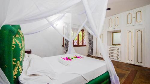 a bedroom with a white bed with flowers on it at Great Rustic Escape 3 bedroom Villa, Casuarina, Malindi in Malindi