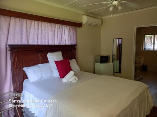 a bedroom with a large white bed with a red pillow at Secret Guest House in Pietermaritzburg
