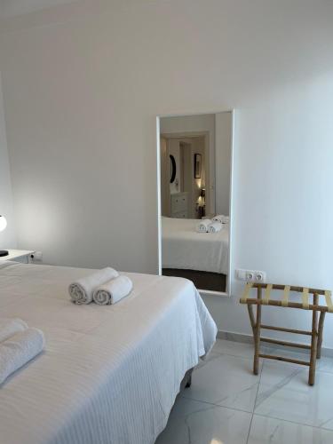 a white bedroom with two beds and a mirror at Central Square apartment by the sea in Ierápetra