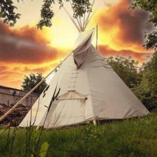 une tente blanche dans un champ avec un coucher de soleil dans l'établissement TeePee OPPIDUM Praha-MotoFamily, à Lhota