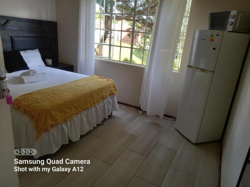 a bedroom with a bed and a refrigerator at Secret guest house in Pietermaritzburg