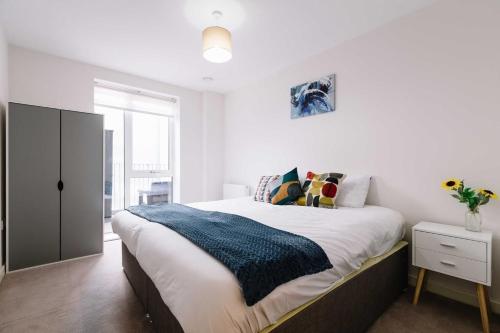 een slaapkamer met een bed met een blauwe deken erop bij Very Modern 17min London Paddington, 8min legoland in Slough