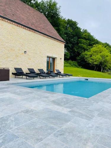 a swimming pool with lounge chairs next to a building at Villa* Piscine* Vue sur château de Beynac in Castelnaud La Chapelle