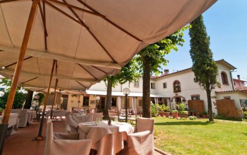 a restaurant with white tables and umbrellas in a yard at La Bussola Da Gino in Quarrata