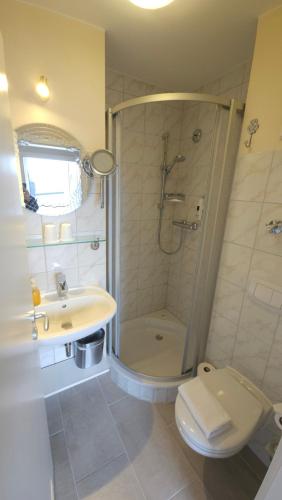 a bathroom with a shower and a toilet and a sink at Hotel Garni Auszeit in Boltenhagen