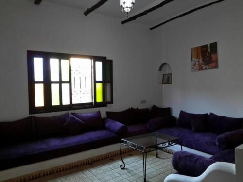 una sala de estar con sofás morados y una mesa. en Chez Zohra, en Taroudant