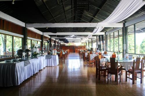 a dining room with tables and chairs and windows at Grand Nirwana Resort Lembang in Tangkubanperahu