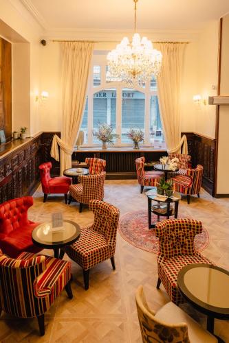 a lobby with tables and chairs and a chandelier at Grand Hôtel de l'Europe - Morlaix Centre in Morlaix