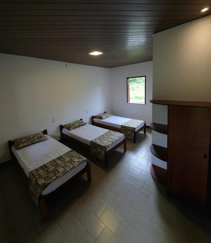 a room with three beds and a tv in it at TEHA Pousada in Ubaíra