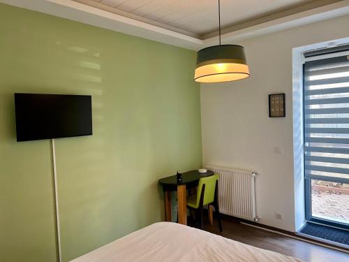 a bedroom with a table and a tv on the wall at De Tussenstop in Villefranche-sur-Saône