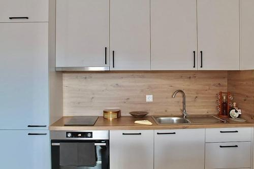 Una cocina con gabinetes blancos y un fregadero. en Apartment Znaor, en Kupres