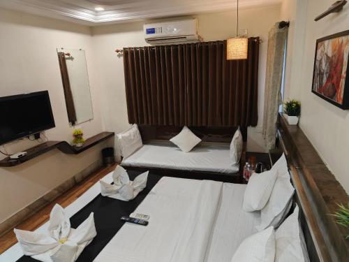 a small living room with a bed and a tv at HOTEL SHIRDI INN in Shirdi
