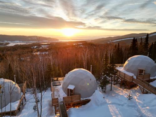 Deux dômes dans la neige avec le coucher du soleil en arrière-plan dans l'établissement Nørdika Charlevoix, à Baie-Saint-Paul