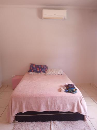 um quarto com uma cama rosa com um bicho de peluche em Suite região central em Ubatuba
