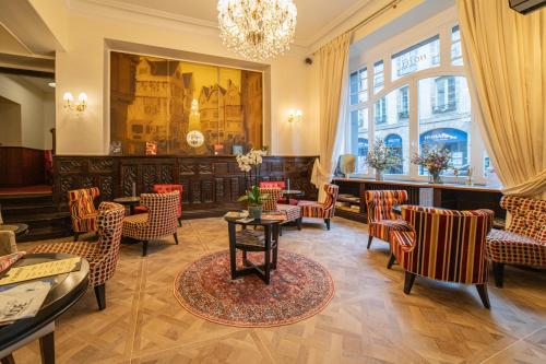 een wachtkamer met stoelen en tafels en een kroonluchter bij Grand Hôtel de l'Europe in Morlaix