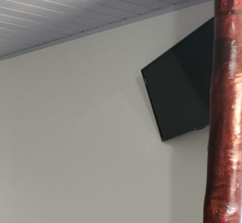 a television on a white wall next to a pole at Bonito HI Hostel e Pousada in Bonito