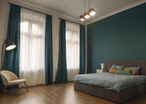 a bedroom with blue walls and a bed and a chair at HiRooms Brașov in Braşov