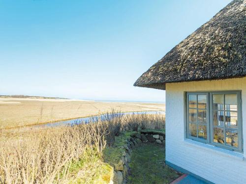 uma casa com um telhado de palha ao lado de um campo em Watthüs von Appartements & Mehr em Kampen