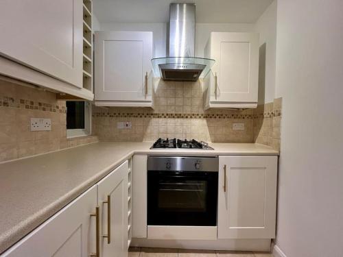 a kitchen with white cabinets and a stove top oven at Treasure Chest Chessington in Ewell