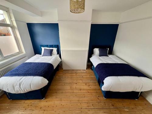 two beds in a room with blue and white at Treasure Chest Chessington in Ewell