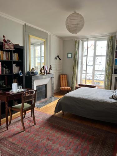 a bedroom with a bed and a desk and a fireplace at Chambre d'hôte in Versailles
