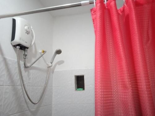 a shower with a red shower curtain in a bathroom at Affordable bedspacer good for 8 with breakfast in Clarin