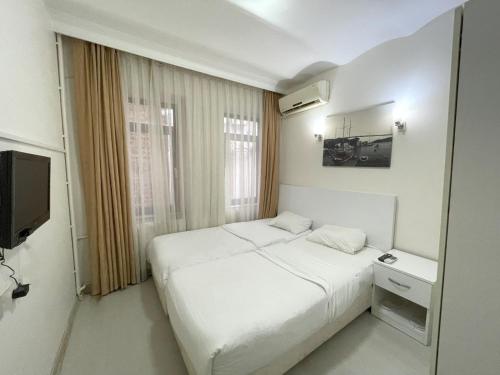 a white bedroom with a bed and a television at Eagle Residence Taksim in Istanbul