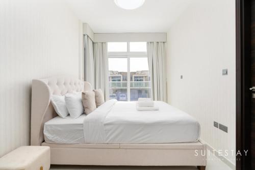 a white bedroom with a large bed with a window at Exceptional 4bed Villa in a Peaceful Community in Dubai