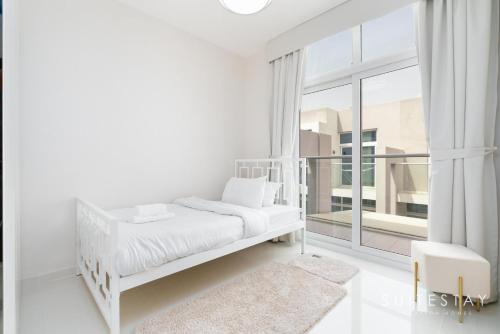 a white bedroom with a bed and a large window at Exceptional 4bed Villa in a Peaceful Community in Dubai