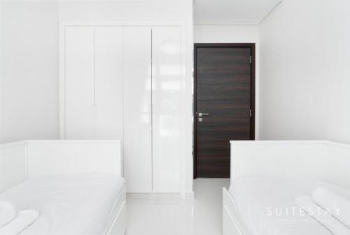 a room with two white beds and a black door at Exceptional 4bed Villa in a Peaceful Community in Dubai