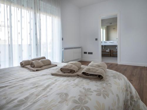 a white bedroom with a bed with towels on it at La Atalaya in Las Navas del Marqués