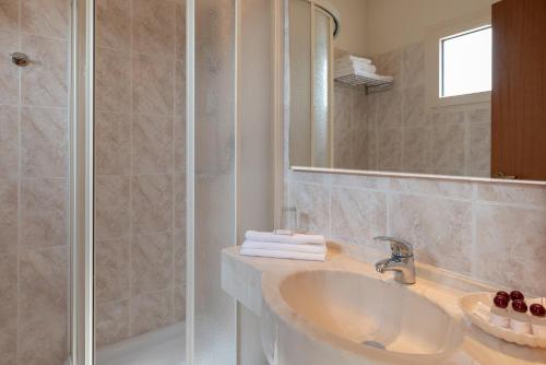 a white bathroom with a sink and a shower at Hotel Tiffany in Rimini