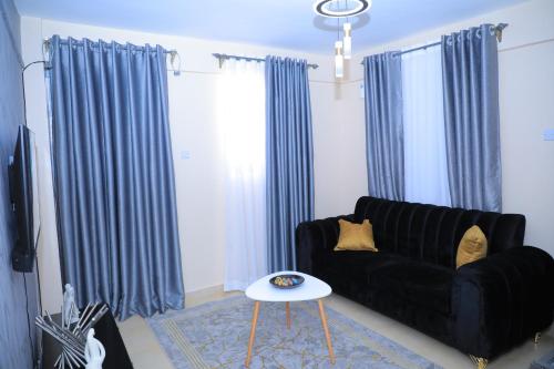 a living room with a black couch and blue curtains at Apartment in kisii Milimani in Kisii