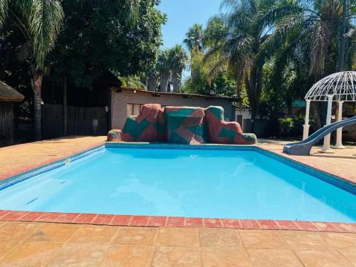 a large blue swimming pool with a slide at Intsingizi bird lodge in Pretoria