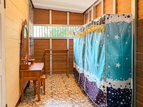 a shower in a room with a table and a window at Baan Panmala Guesthouse - Ao Luek in Krabi town