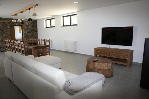 a living room with a white couch and a flat screen tv at Casa da Teresinha in Bragança