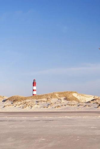 a red and white lighthouse sitting on top of a hill at Dünencamping Amrum in Wittdün