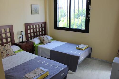 Cette chambre comprend 2 lits et une fenêtre. dans l'établissement Townhouse Estepona, à Estepona