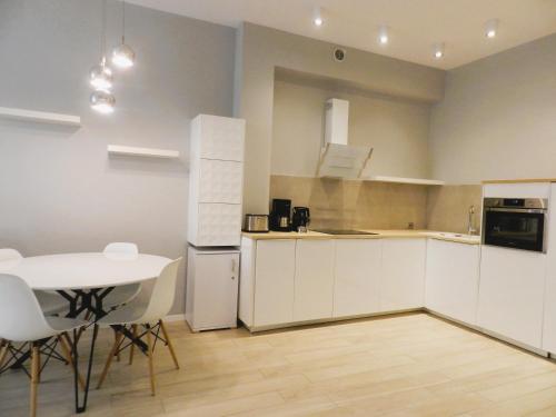 - une cuisine avec des placards blancs, une table et des chaises dans l'établissement Apartament Donnka, à Cracovie