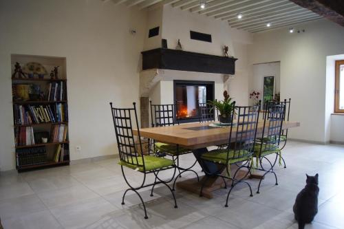 - une salle à manger avec une table, des chaises et un chat dans l'établissement La Maison de Rochebois, chambres et table d'hôtes, Savoie, France, à Champagneux
