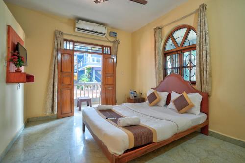 a bedroom with a bed and a large window at Oceanside Beach House-By Roseal in Baga